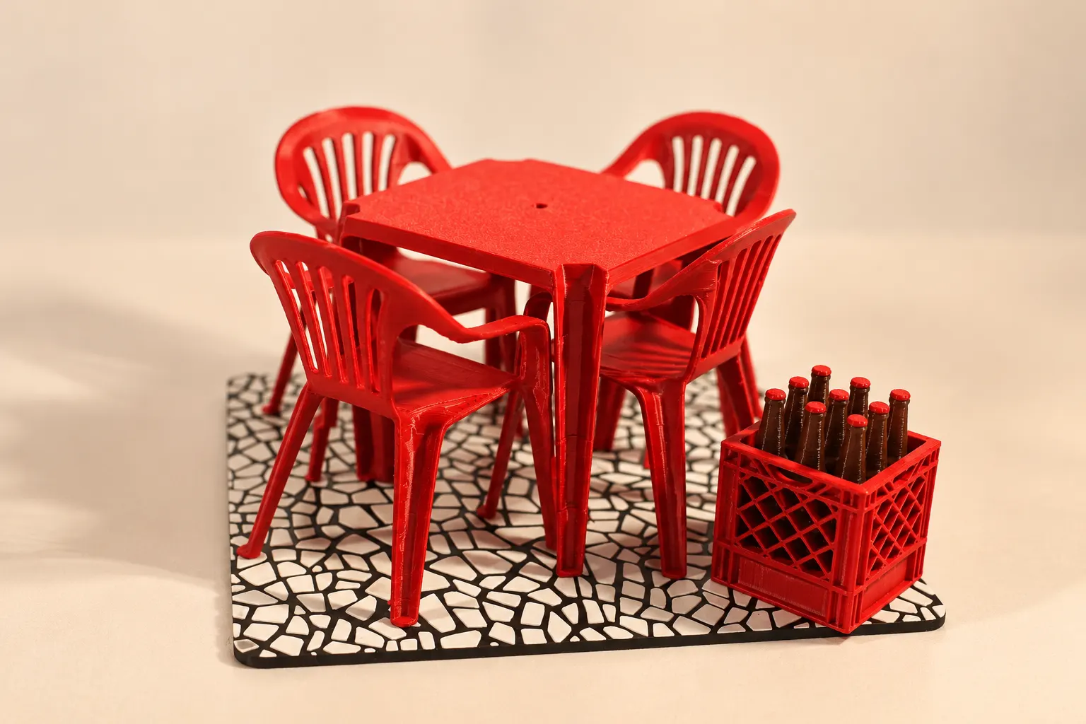 Miniatura de mesa de bar vermelha com quatro cadeiras e engradado de garrafas sobre piso de pedras